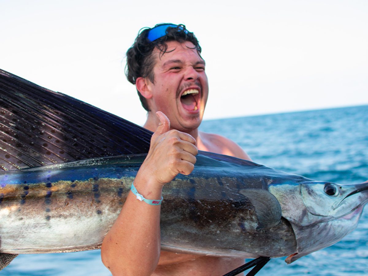 Happy angler embracing a huge freshly caught Marlin on a deep-sea fishing trip in Puerto Vallarta.
