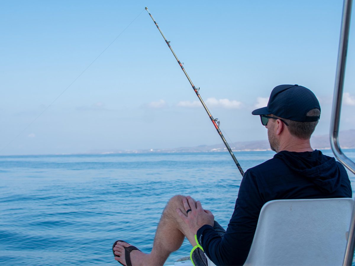 Angler looking at the calm ocean horizon to prevent seasickness during a boat tour.