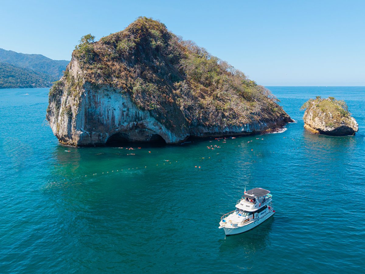 Panoramic view of Los Arcos rock formation with the Florero boat anchored in Puerto Vallarta.