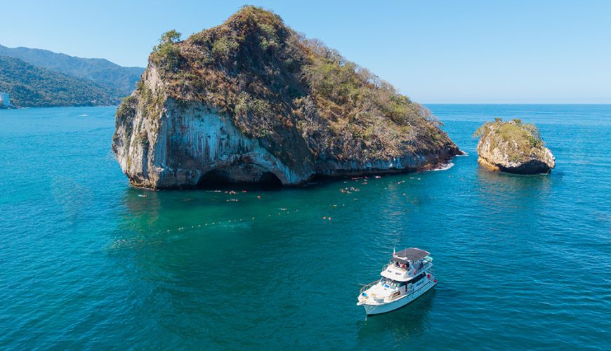 Panoramic view of Los Arcos rock formation with the Florero boat anchored in Puerto Vallarta.