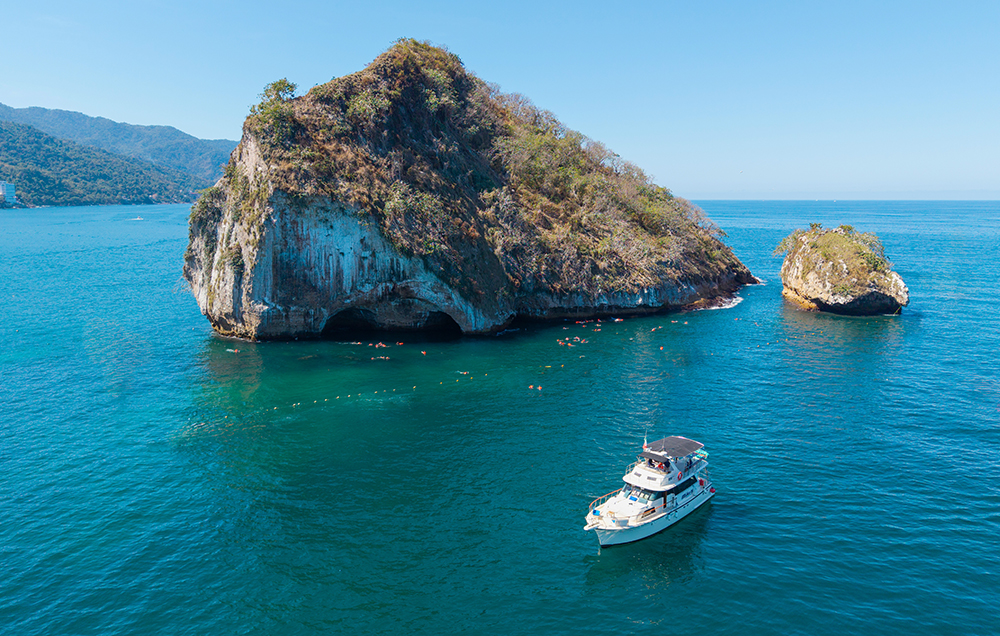Panoramic view of Los Arcos rock formation with the Florero boat anchored in Puerto Vallarta.